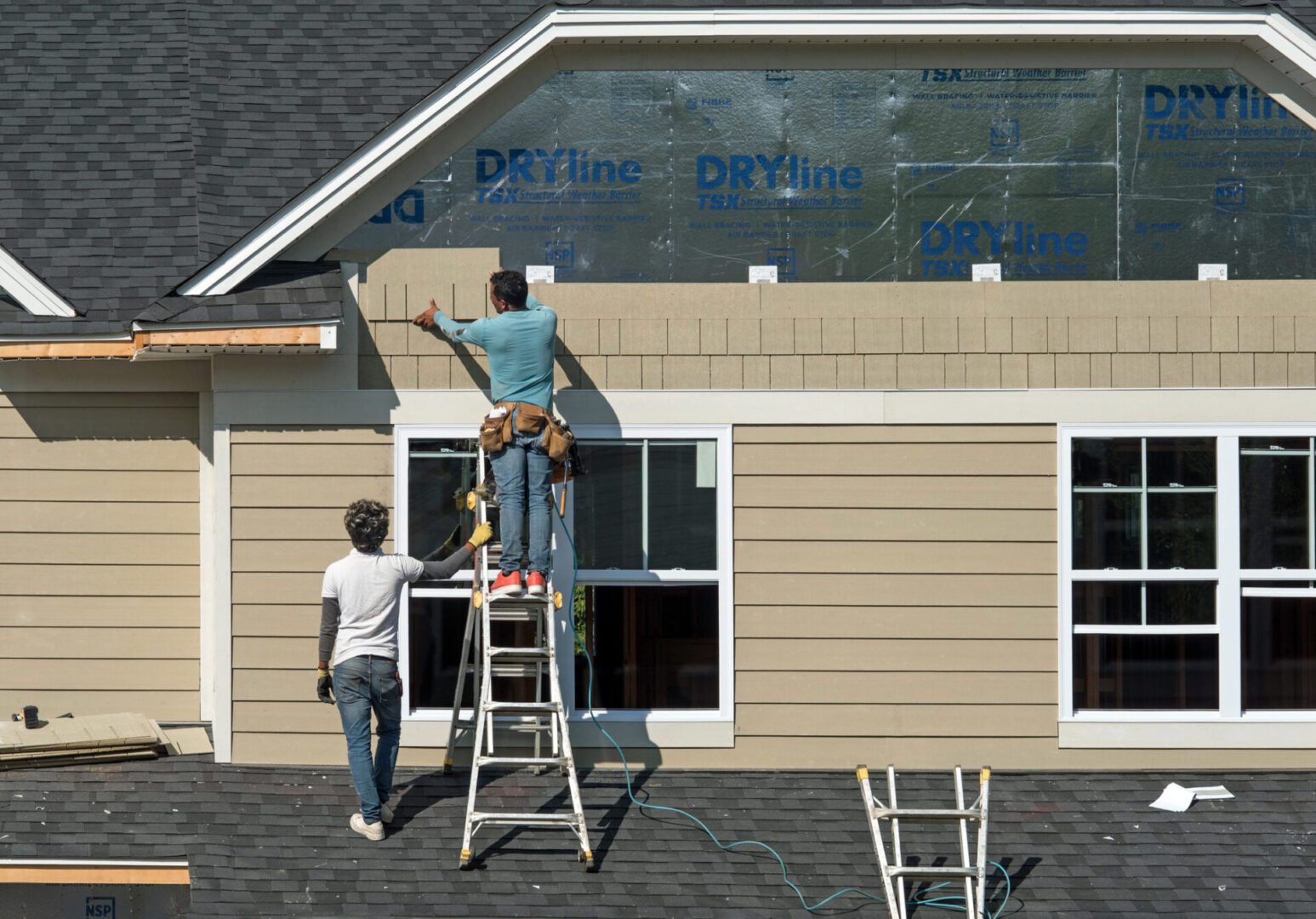 Two men working on house siding